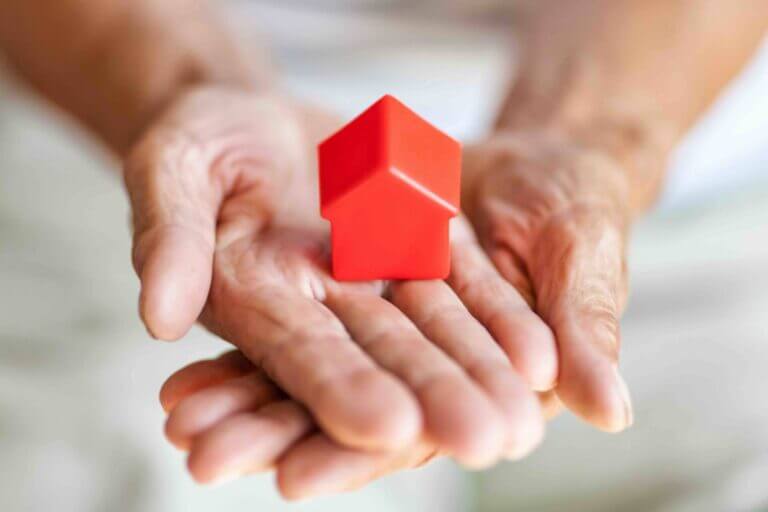 Elderly woman holding a small house in her hands