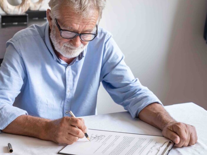 Senior old man elderly examining and signing last will and testament