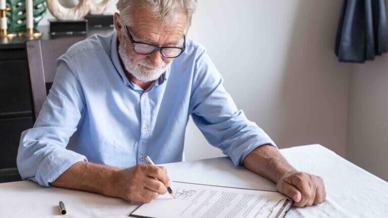 Senior old man elderly examining and signing last will and testament