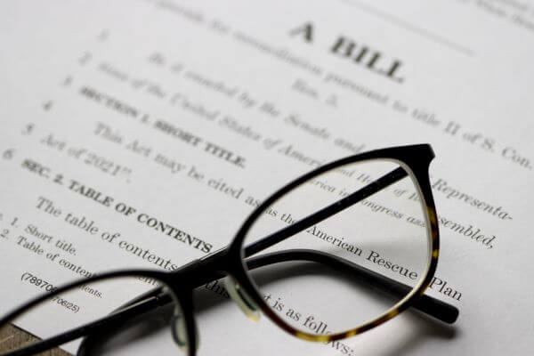 reading glasses resting on paper with the title of "A BILL"