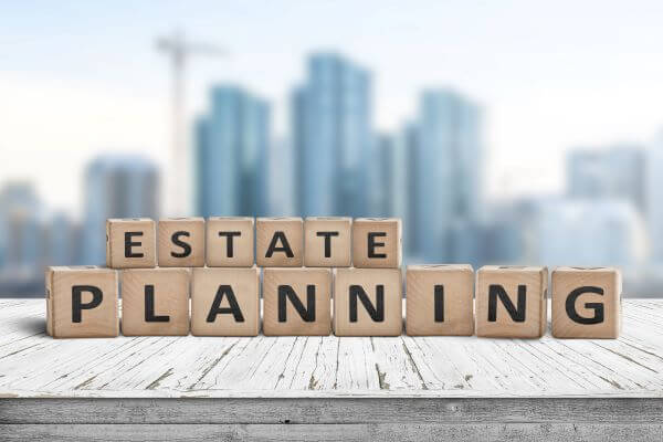 Estate Planning spelled on a wooden blocks with cityscape blurred in background