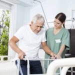 Nurse helps older man with walker in hospital room