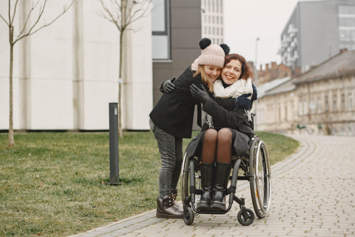 Mother with special needs in a wheelchair with her daughter embracing at park