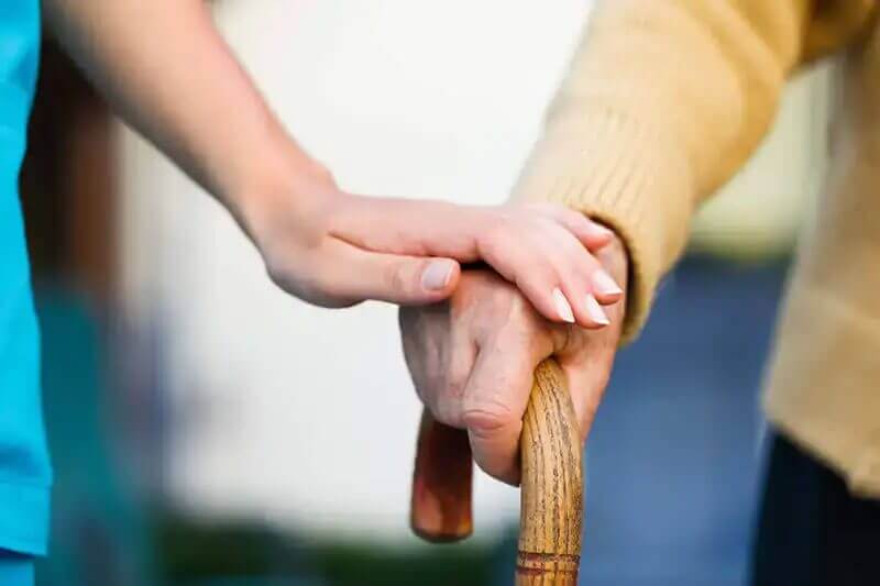 caregiver holds elder's hand