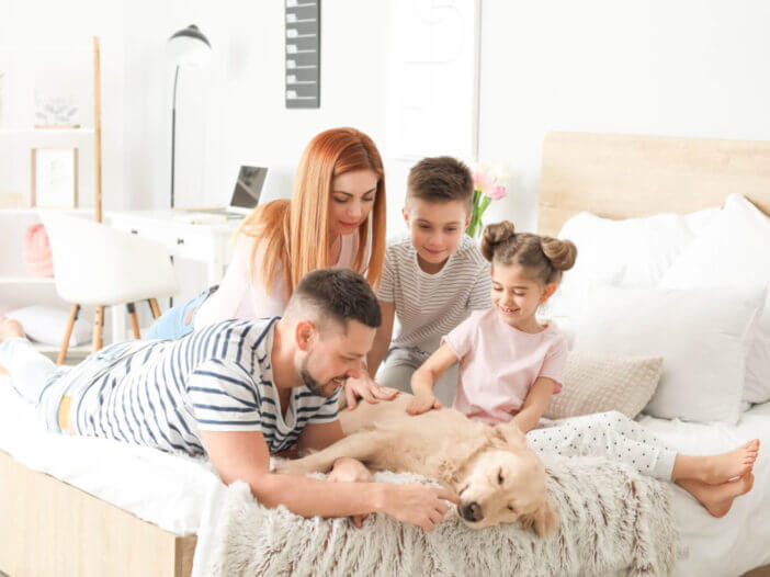 Happy family with dog in bedroom at home