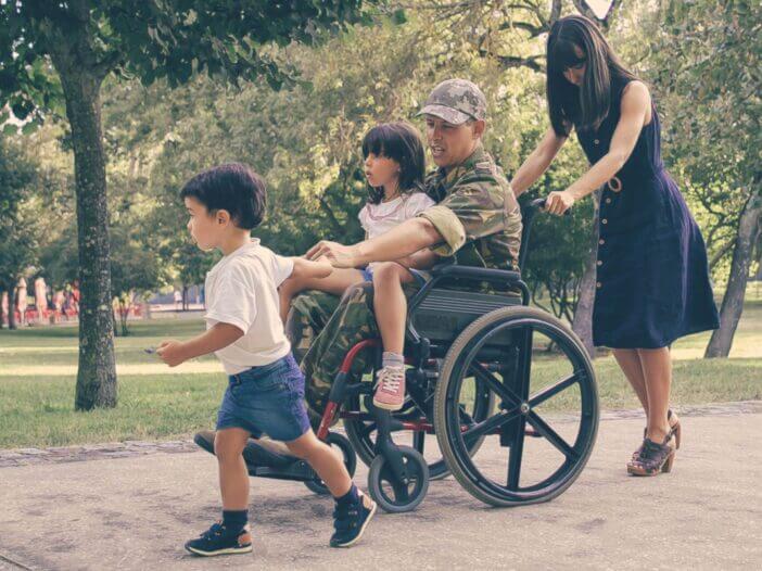 Disabled man in military uniform walking with wife and kids