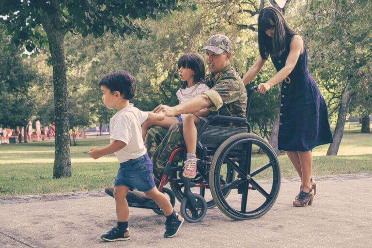 Disabled man in military uniform walking with wife and kids
