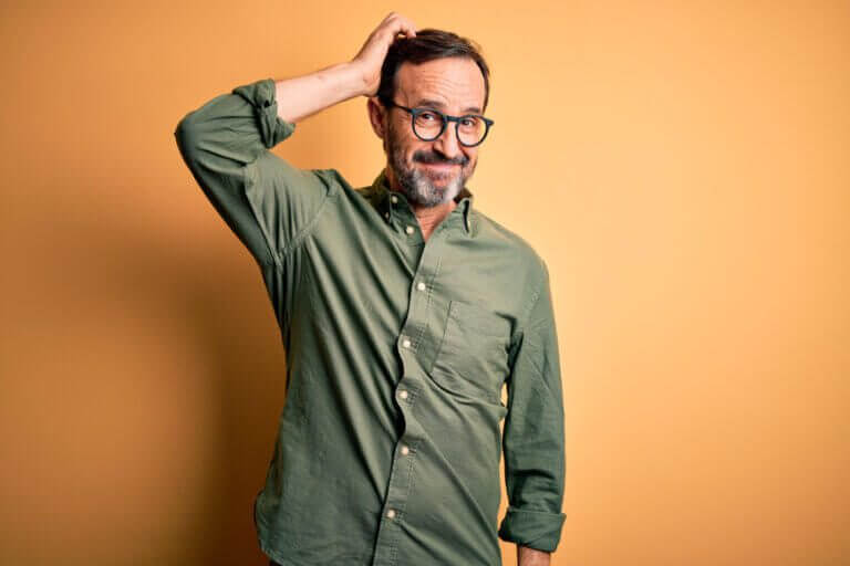 Man thinking about how to choose a trustee for his trust in a green shirt on an orange background