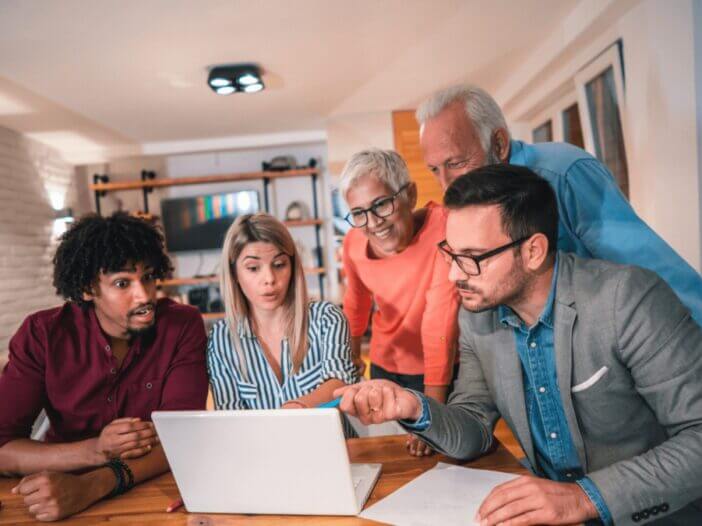 group of people looking at a laptop screen