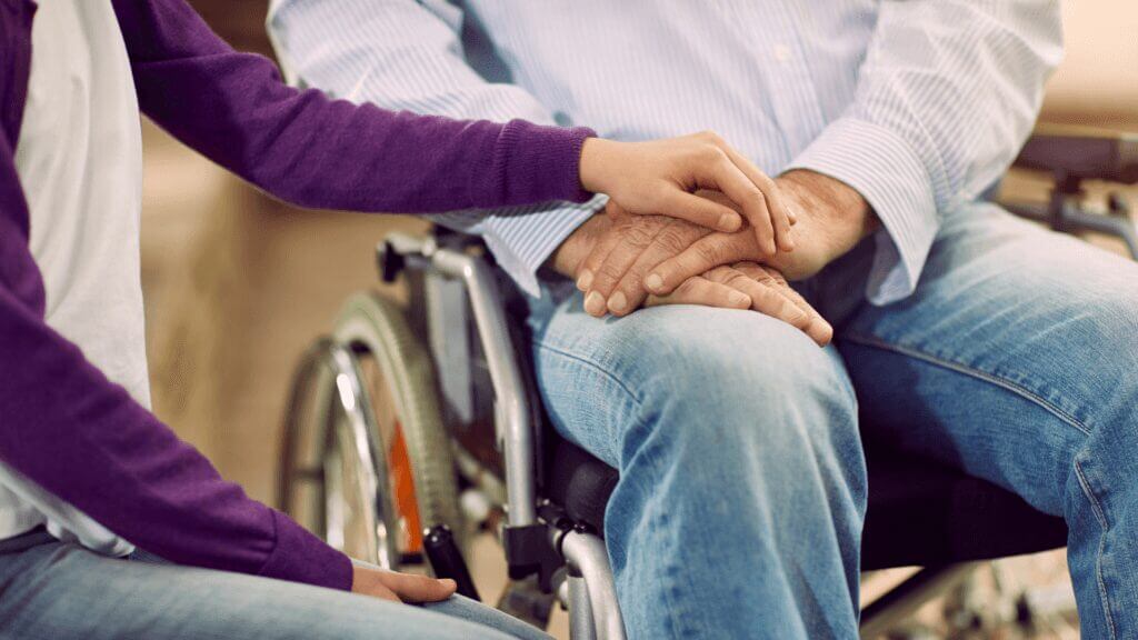 person in wheel chair holding hands with another person