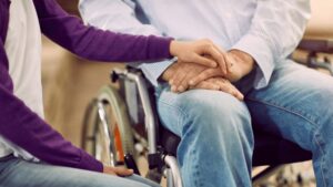 person in wheel chair holding hands with another person