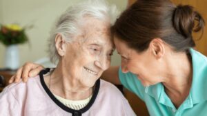 old women hugging younger women with foreheads touching