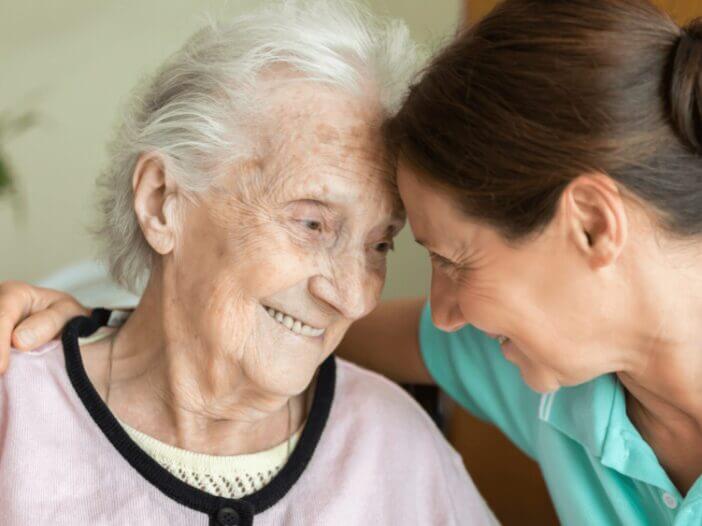 old women hugging younger women with foreheads touching