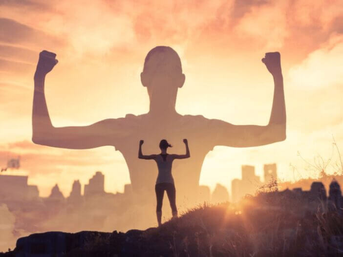 girl standing on mountain flexing arm muscles