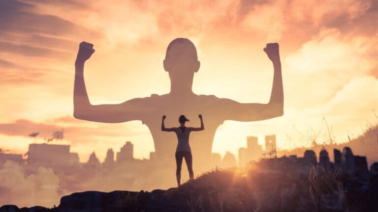 girl standing on mountain flexing arm muscles