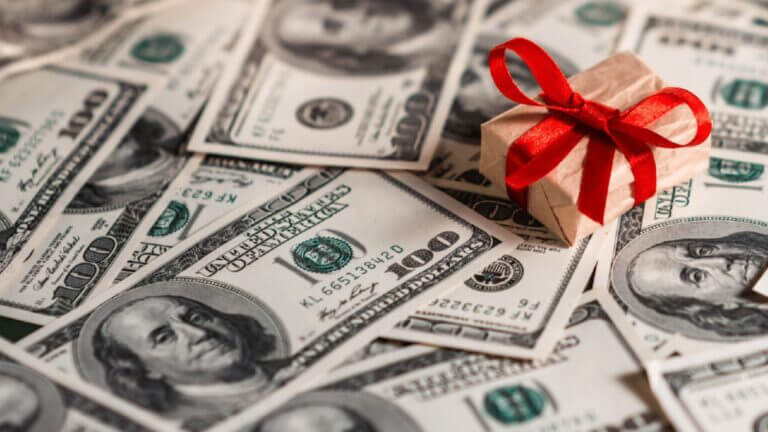 money with a present on top of it with a red bow