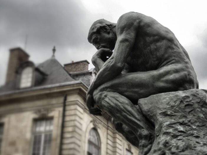 "The Thinker" statue. Statue is kneeled with his hand on his head thinking.