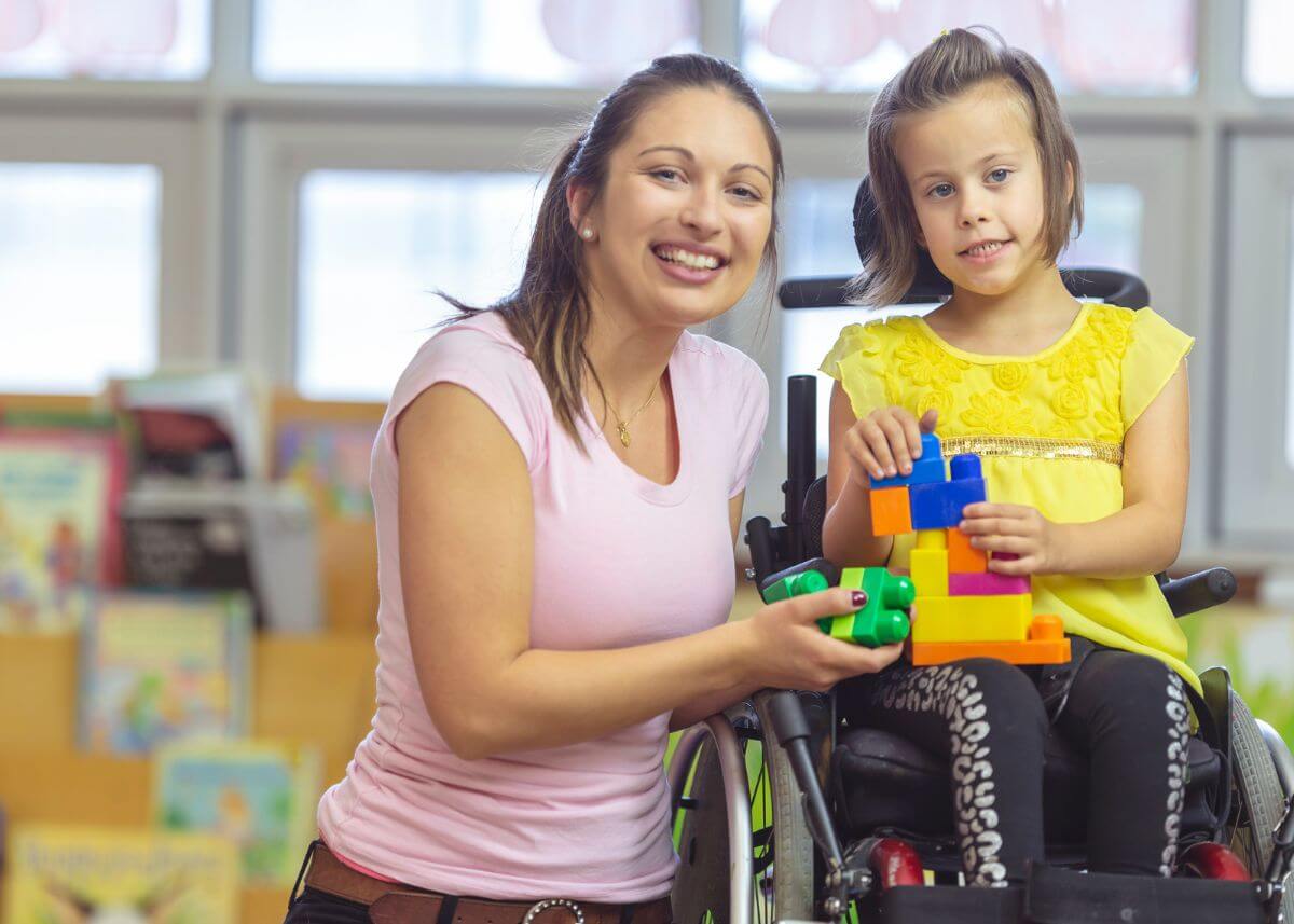 little girl in wheel chair playing with blocks with her caregiver