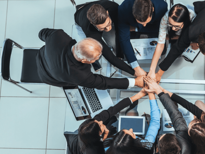 business team meeting with hands together in a circle