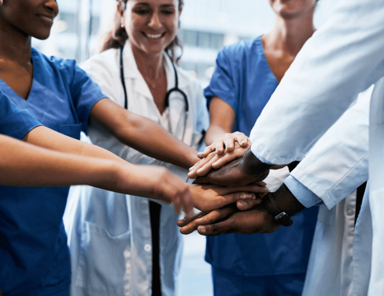 Medical professionals in a circle with their hands in