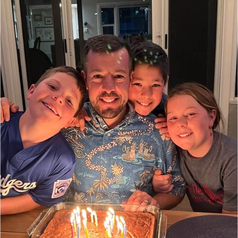 dad having cake with three young kids