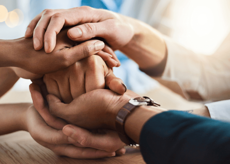 multiple people putting hands together in a pile