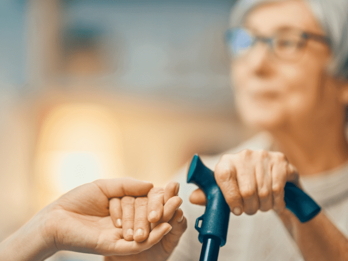 Elderly woman holding a can and holding on to another person's hand