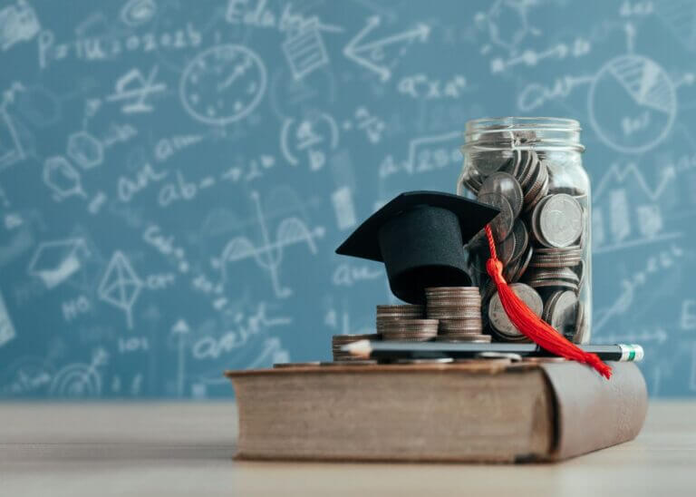 jar of money and grad cap sitting on top of a textbook