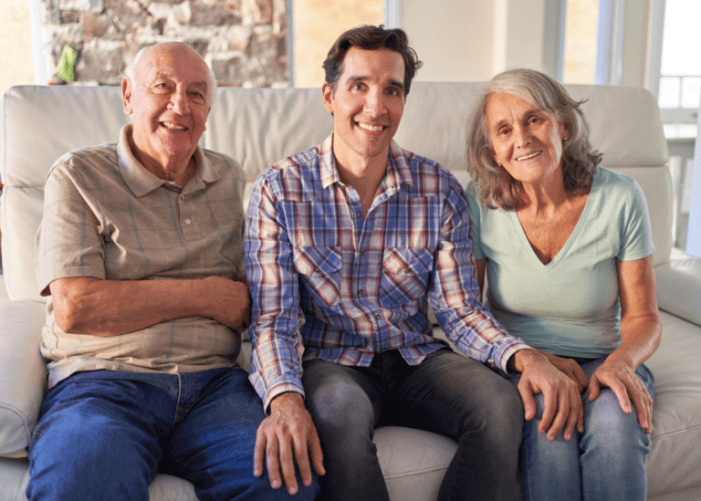 adult son sitting with aging parents on the couch