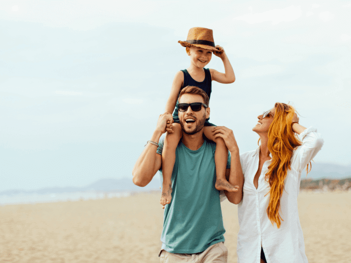 family walking on the beach with little boy on dad's shoulders