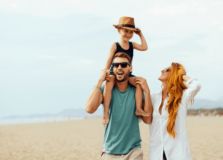 family walking on the beach with little boy on dad's shoulders