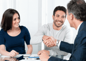 young couple shaking older advisors hand and smiling