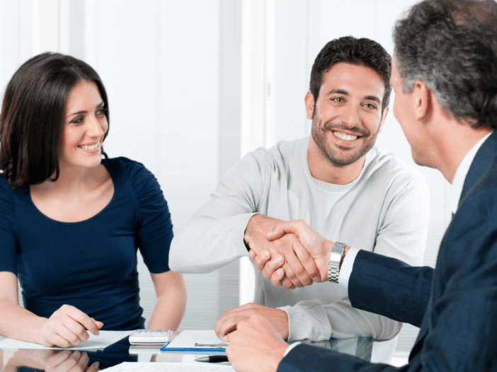 young couple shaking older advisors hand and smiling