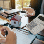 man with calculator and financial documents spread out on the table