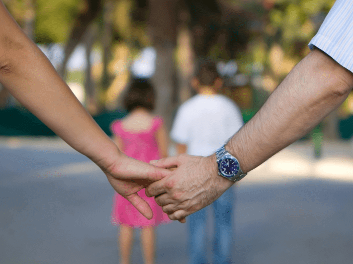 parents holding hands with kids in the distance