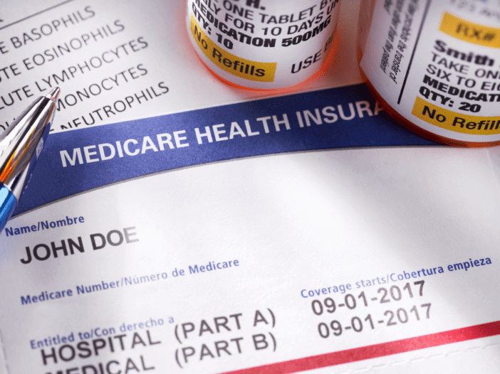 Medicare health insurance card with pill bottles next to it