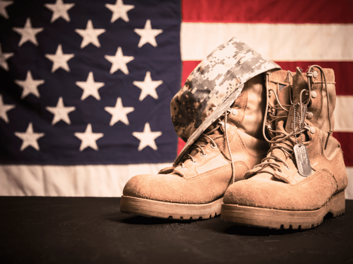 american flag with miliary boots, dog tag, and military hat