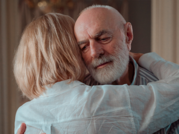 Elderly couple hugging and looking emotional