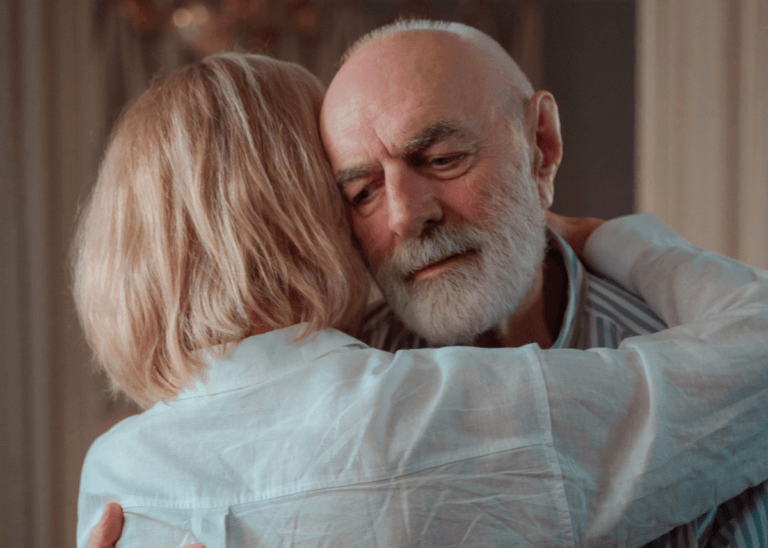 Elderly couple hugging and looking emotional