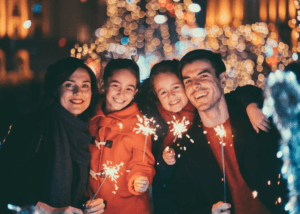 Parents with two young girls lighting sparklers on new years