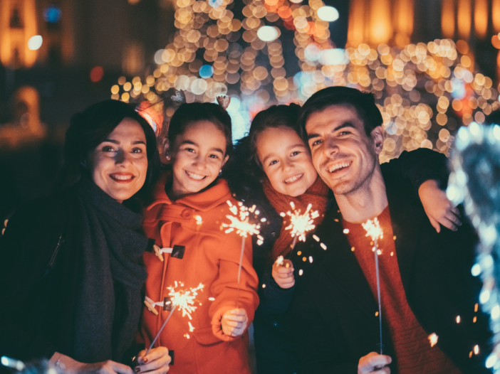 Parents with two young girls lighting sparklers on new years