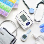 healthcare items all scattered on a table- gloves, thermometer, stethoscope, etc.