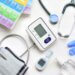 healthcare items all scattered on a table- gloves, thermometer, stethoscope, etc.