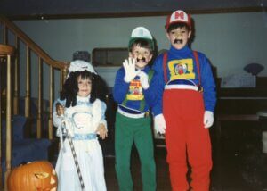 kevin when he was younger with his two siblings standing to the left of him. him and his brother are next to each other dressed up as mario and luigi and his sister is dresses up as little bo peep.