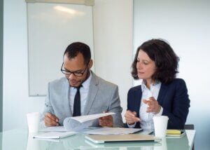 A woman discussing legal documents with a professional in an office setting.