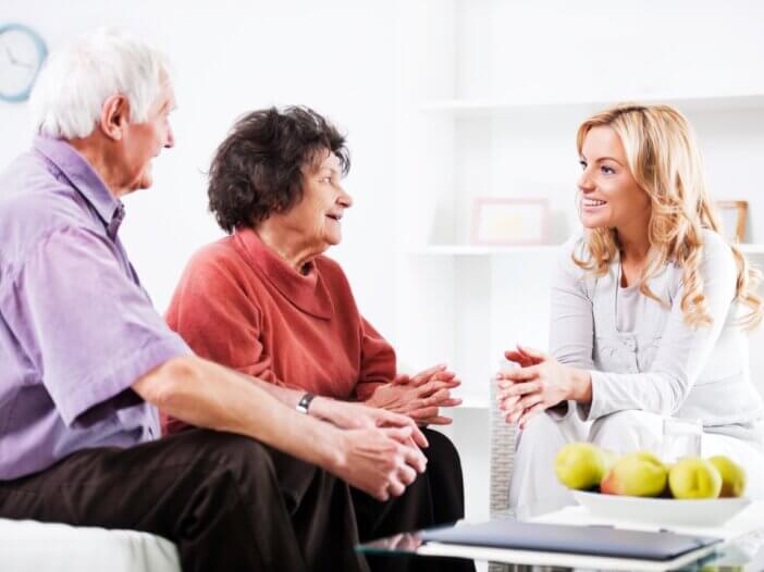 an older couple sitting on a couch and across from them a professional sitting on a couch smiling