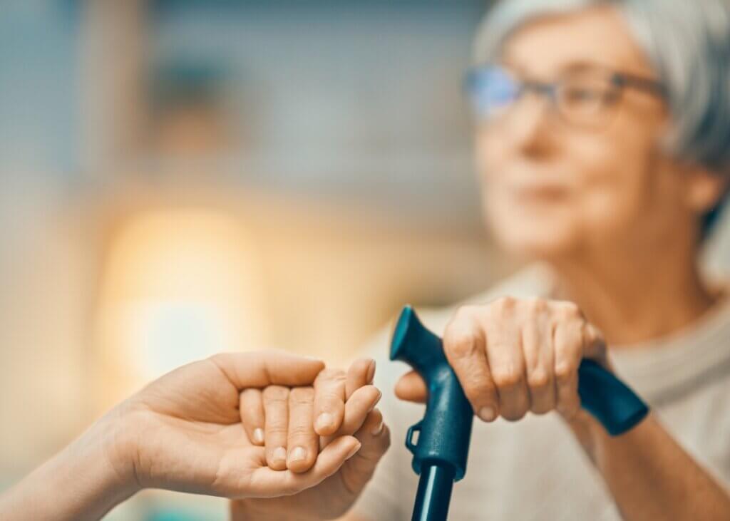 a picture of an older woman holding her cane and then holding the hand of a younger person