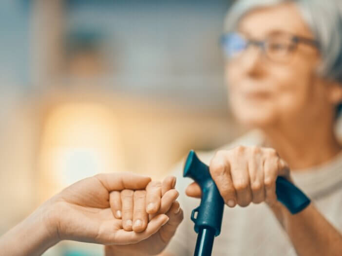 a picture of an older woman holding her cane and then holding the hand of a younger person