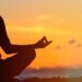 a person meditating with the sunset in the background