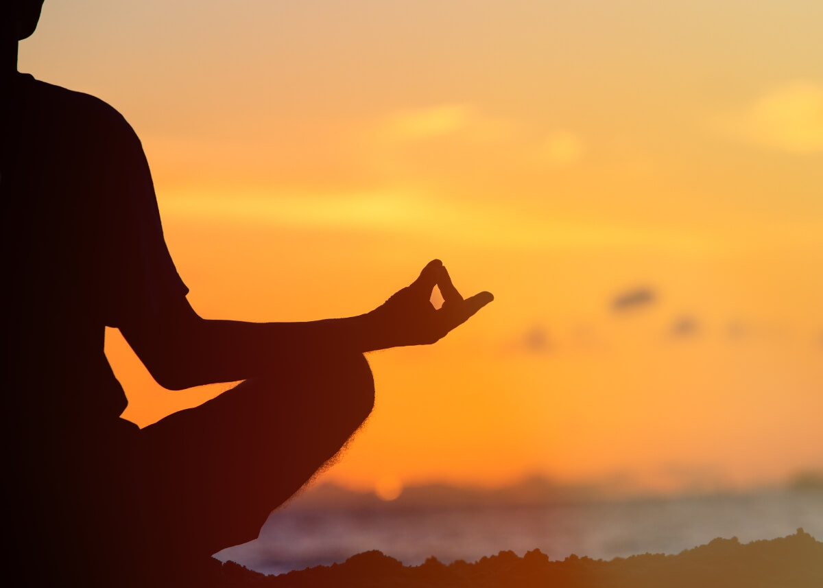 a person meditating with the sunset in the background